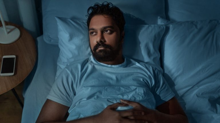 Bearded man lying awake in bed