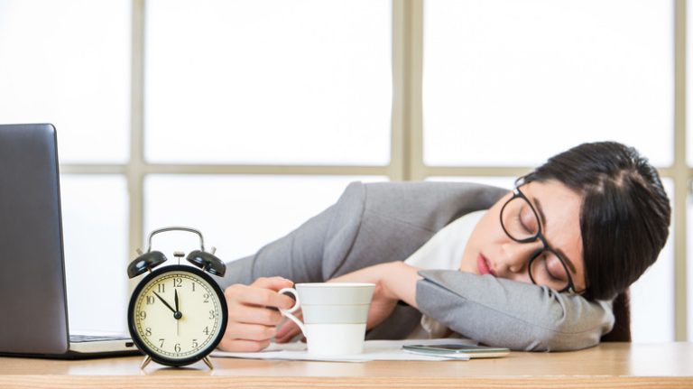 A woman sleeping at her desk at her office