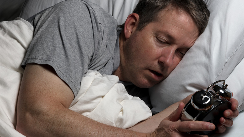 Man asleep holding a clock