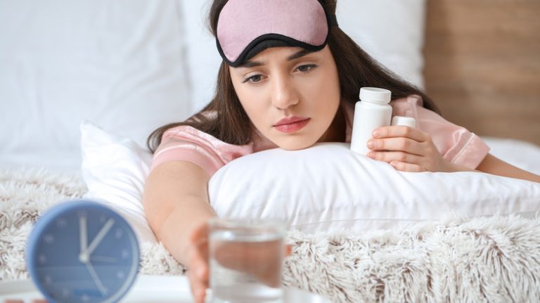 Woman with sleeping pills grabbing water