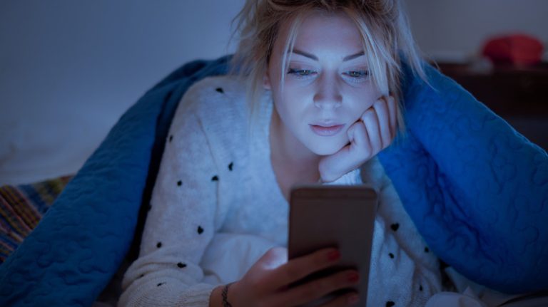 Woman looking at phone in bed