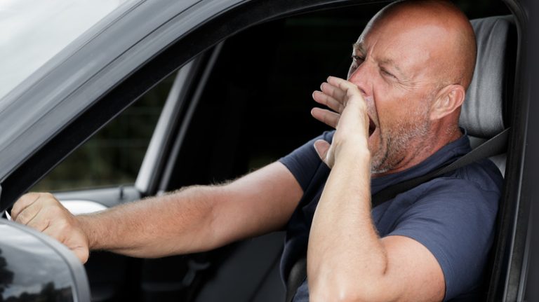 Man yawning in car