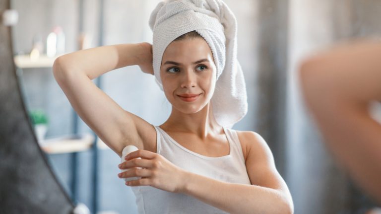 woman in bathroom applying deodorant