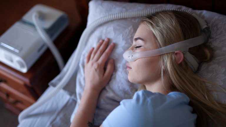 Young woman sleeping with CPAP machine
