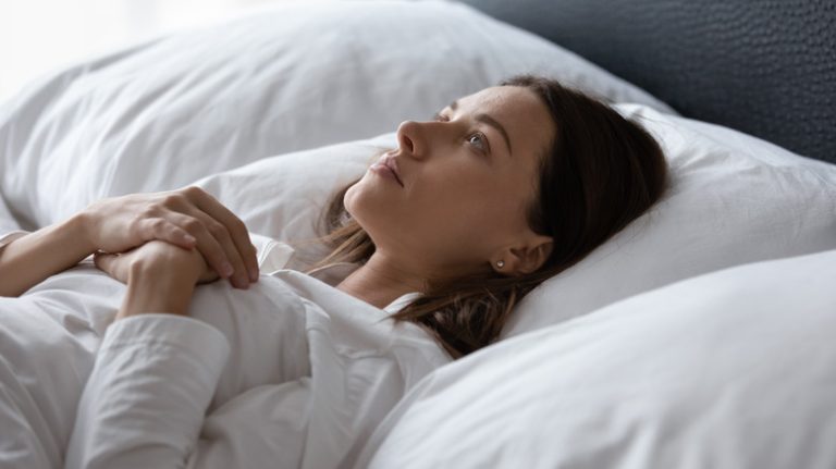 Side view of a woman lying in bed wide awake