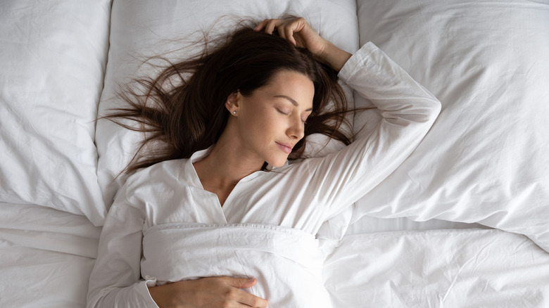 woman sleeping soundly in white sheets and pajamas