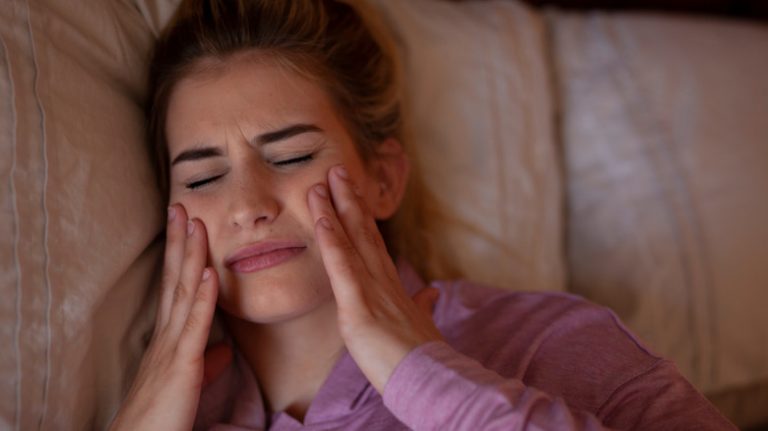 woman with bruxism massaging face