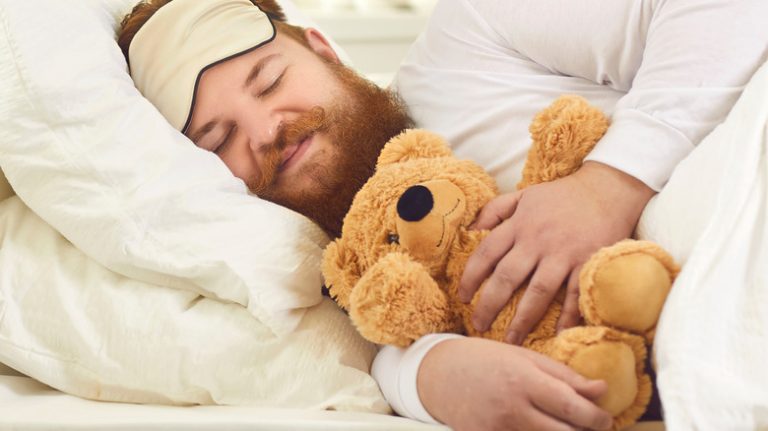 happy sleeping man hugging teddy bear