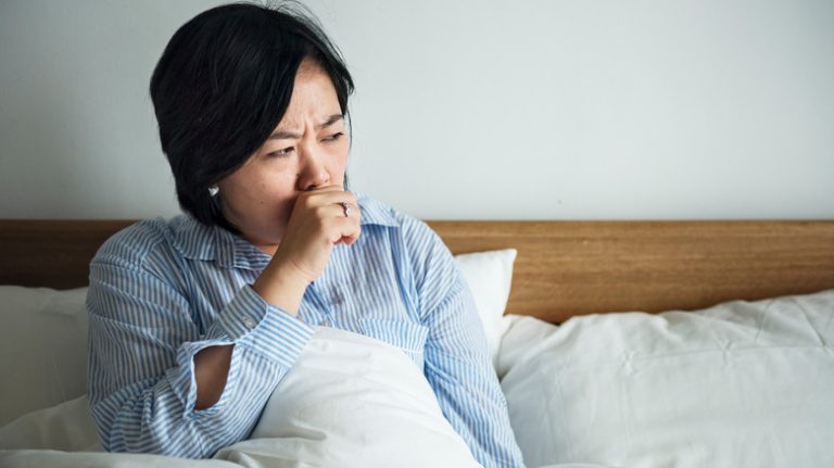 Woman coughing in bed