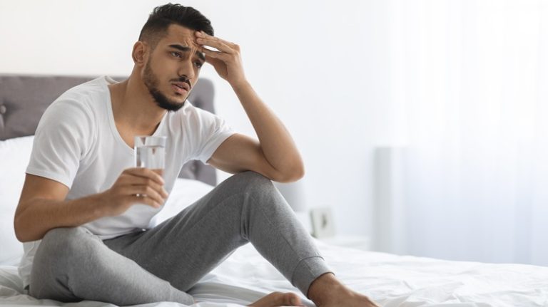 Man sitting in bed with headache