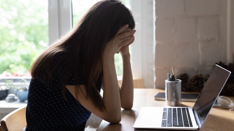 person with head in hands at desk