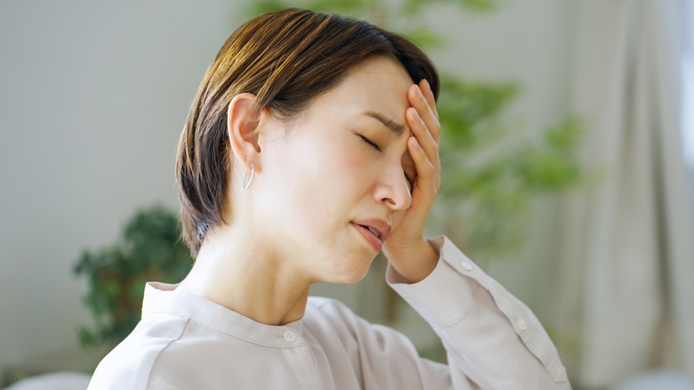 Woman holding head in pain