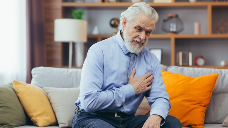 Man on couch holding chest