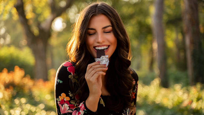 woman eating a bar of dark chocolate