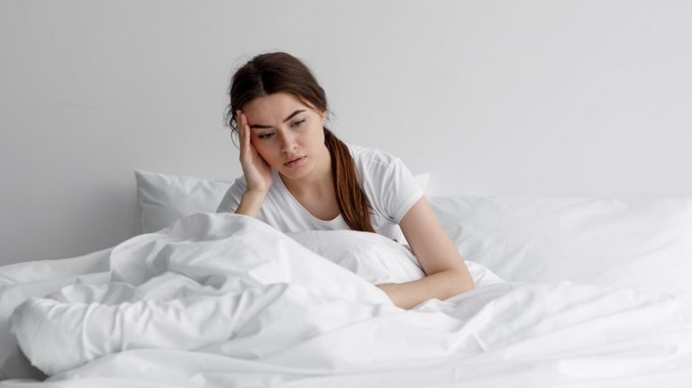 woman sitting sadly in bed