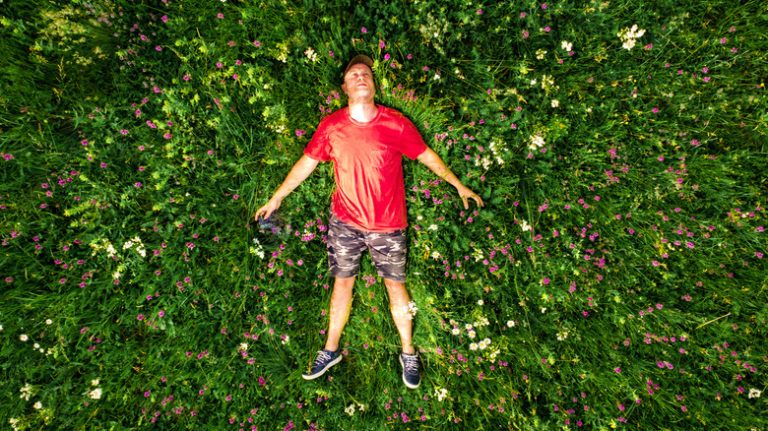 Man lies happily on tapestry lawn