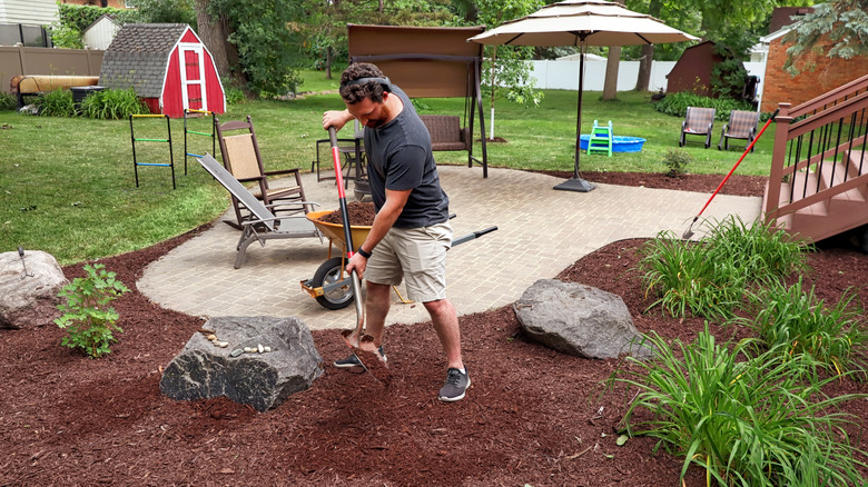 man spreading back yard mulch