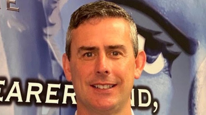 Dr. Jarrod Spencer standing in front of a promo sign for his book