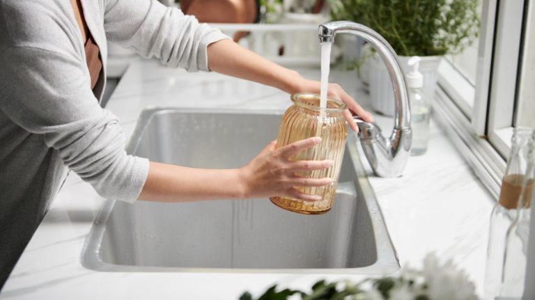 person filling vase with water