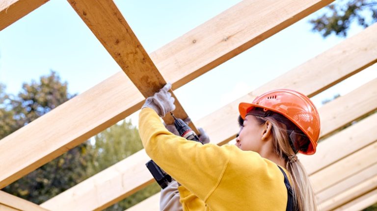 woman drilling into a wood frame