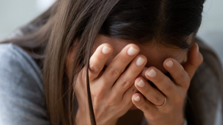 Woman experiencing depression sits with her head in her hands