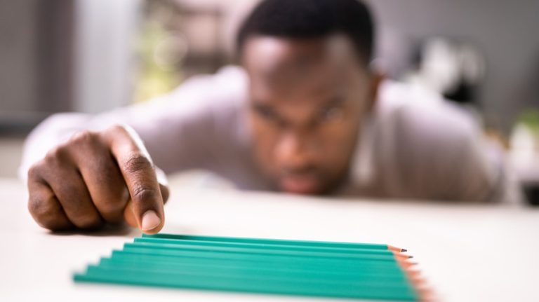 man lining up pencils in perfect rows