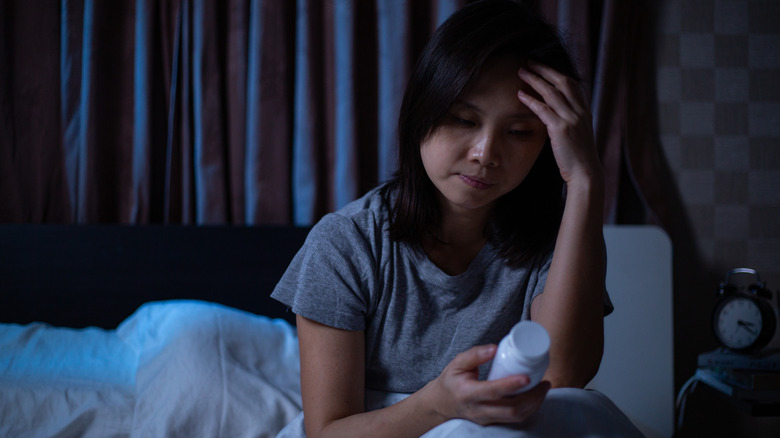 Anxious woman looking at pill bottle