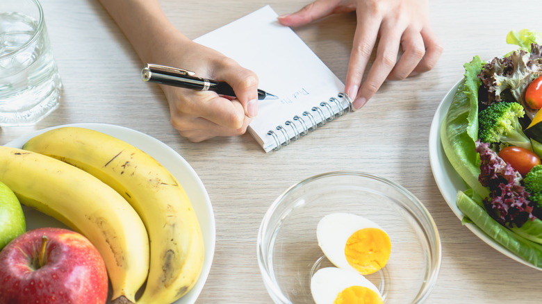 Person records calories on notepad