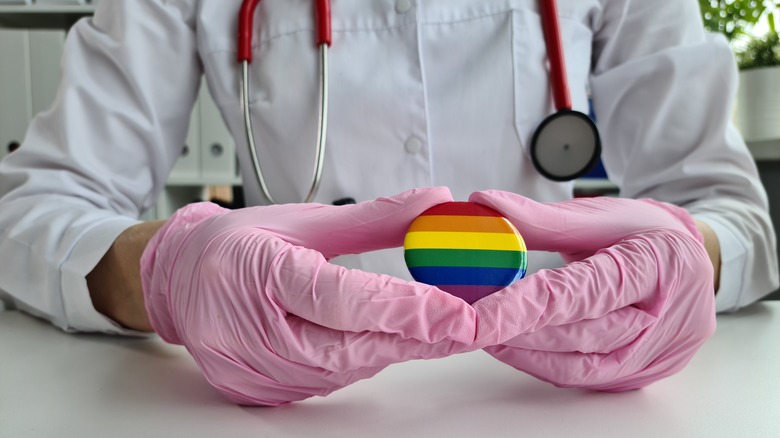 Doctor holding rainbow pin in gloved hands