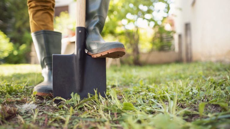 person digging grass with a shovel