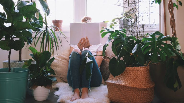 Woman reads surrounded by houseplants