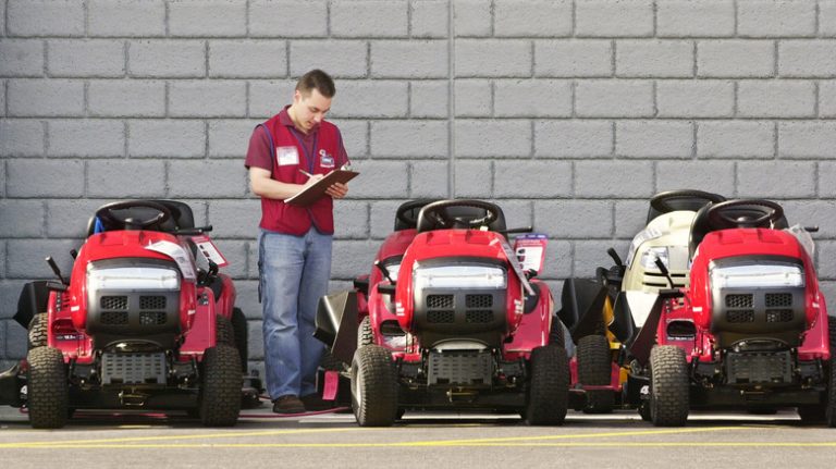 man inspecting riding mowers