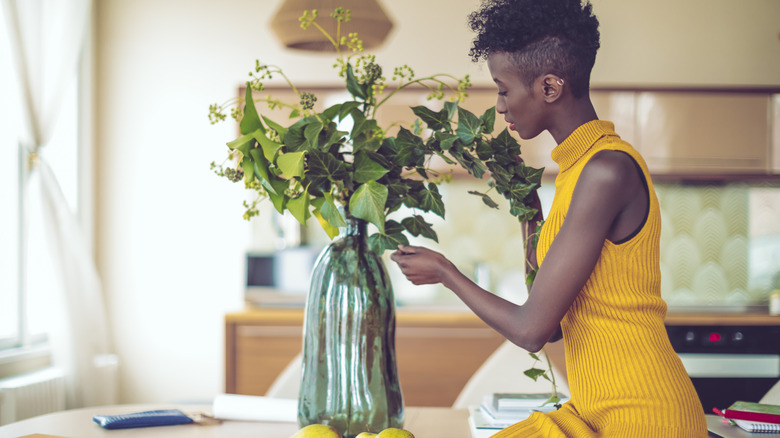 woman tending to plant in vase