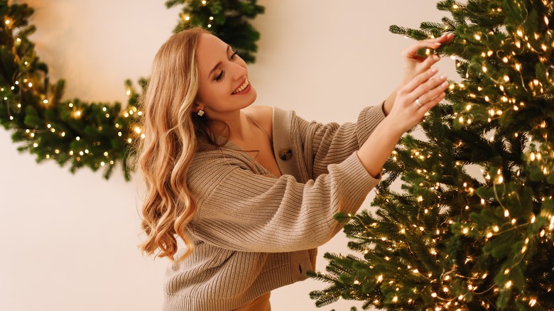 woman fluffing Christmas tree branches